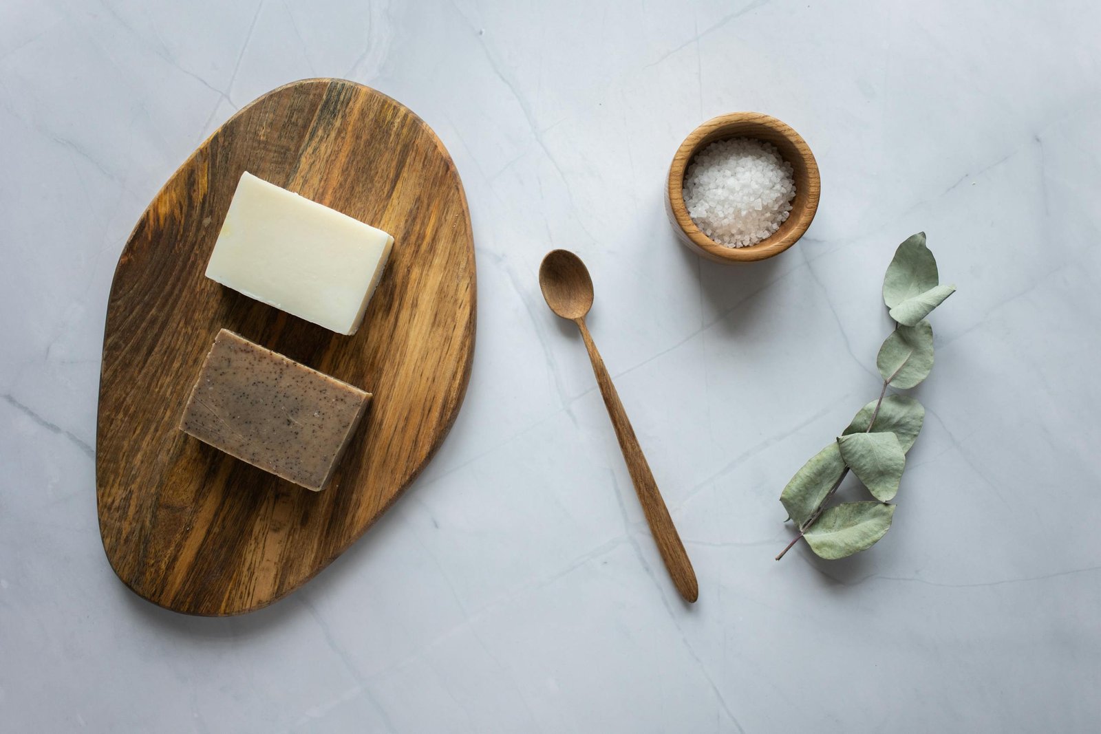 Homemade soap on wooden board near scrub with salt