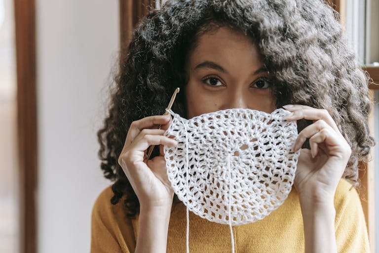 Young woman covering mouth with white crochet napkin