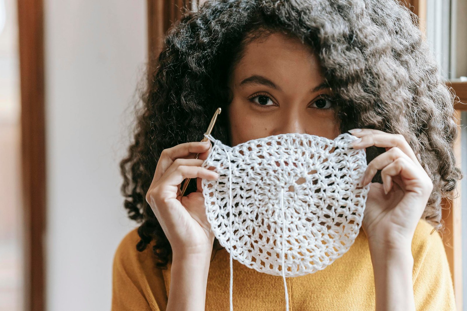 Young woman covering mouth with white crochet napkin