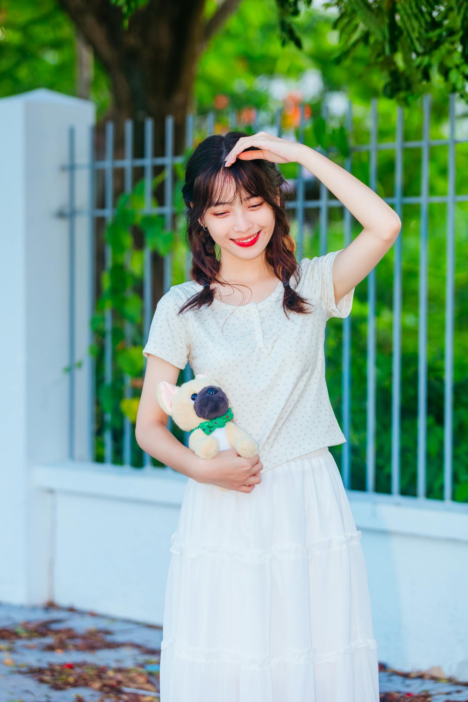 A woman in white skirt and white top holding a teddy bear