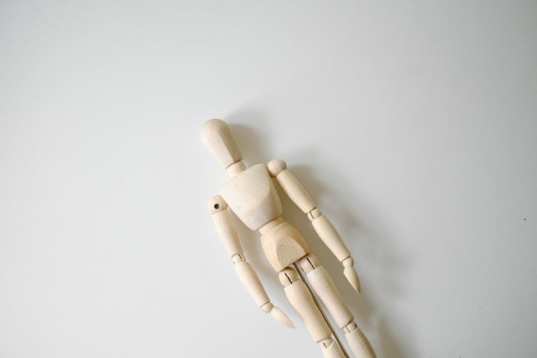 A wooden mannequin on a white surface