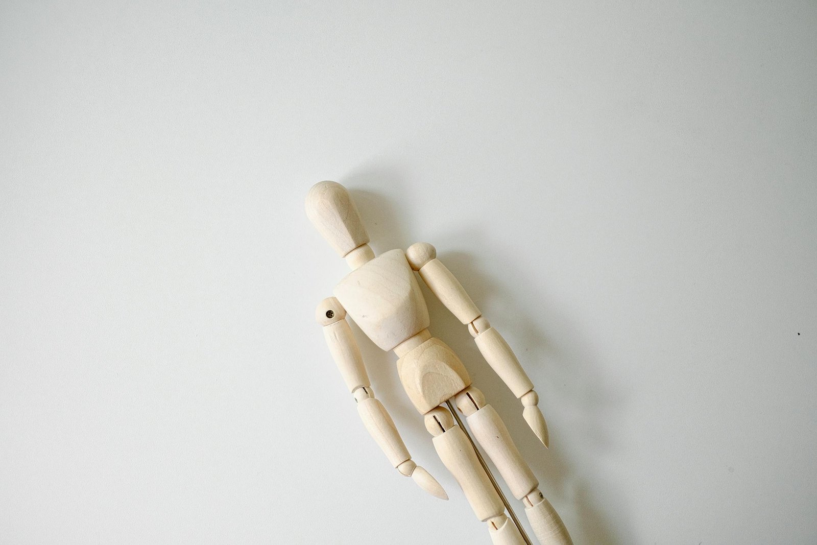 A wooden mannequin on a white surface