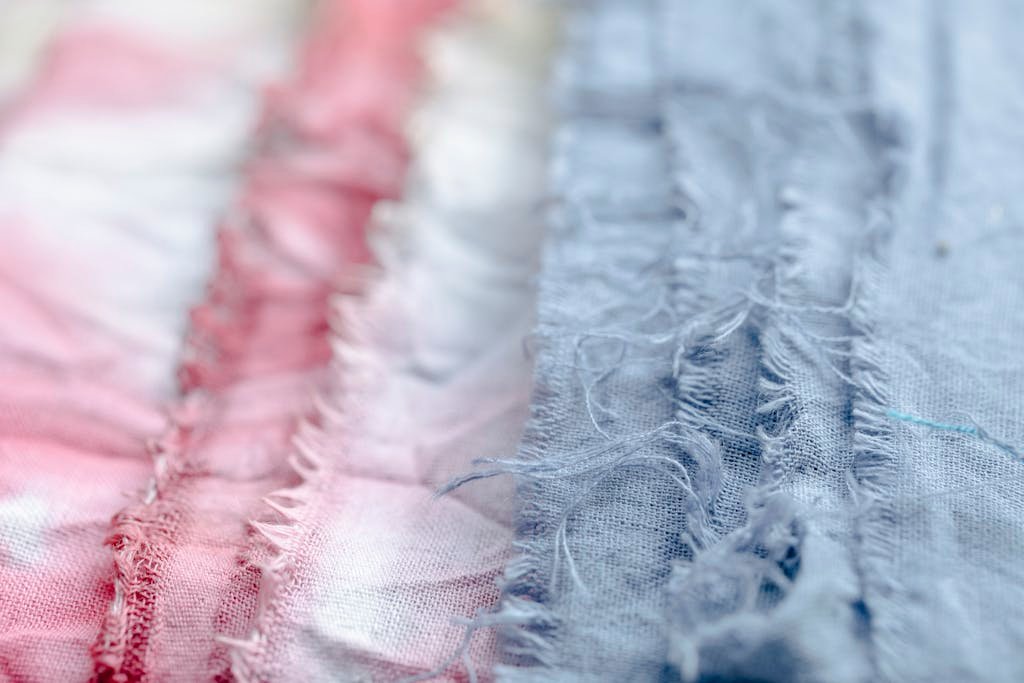 Blue and pink textile with threads placed on surface in modern professional studio on blurred background during production of clothes