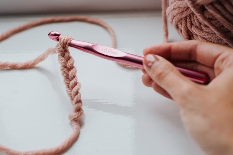 Faceless person knitting in bright room