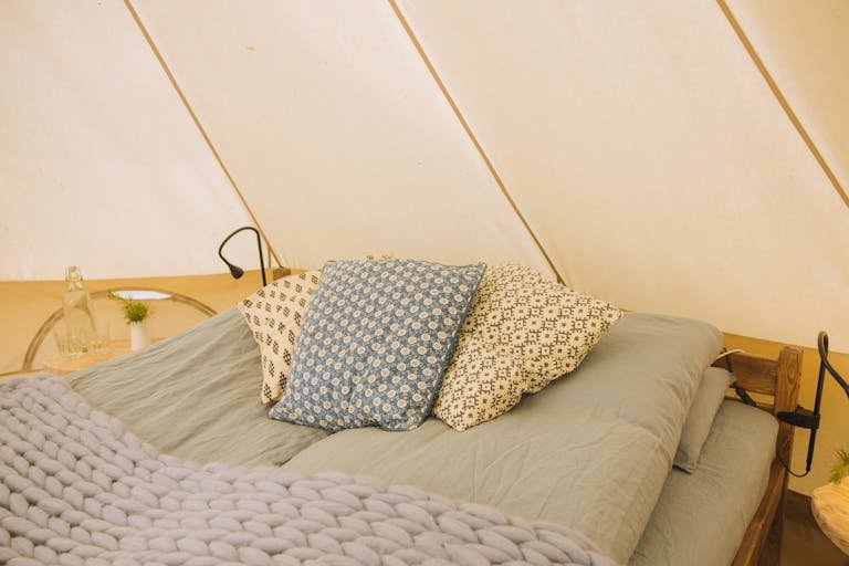 Inviting bedroom setup with patterned cushions and a knitted blanket for a cozy feel.